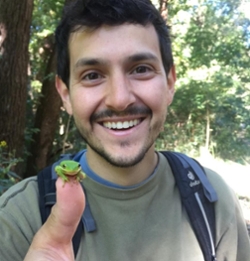 Image of Alex Krohn smiling with a frog on his finger.