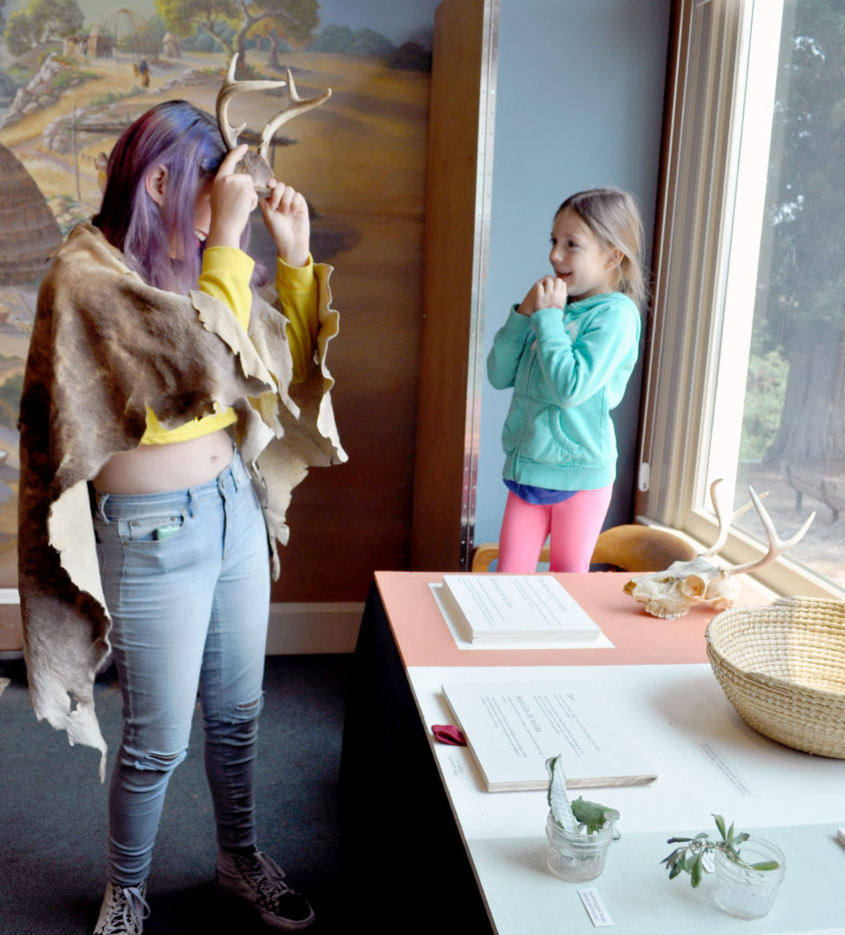 woman and girl play with a pair of antlers