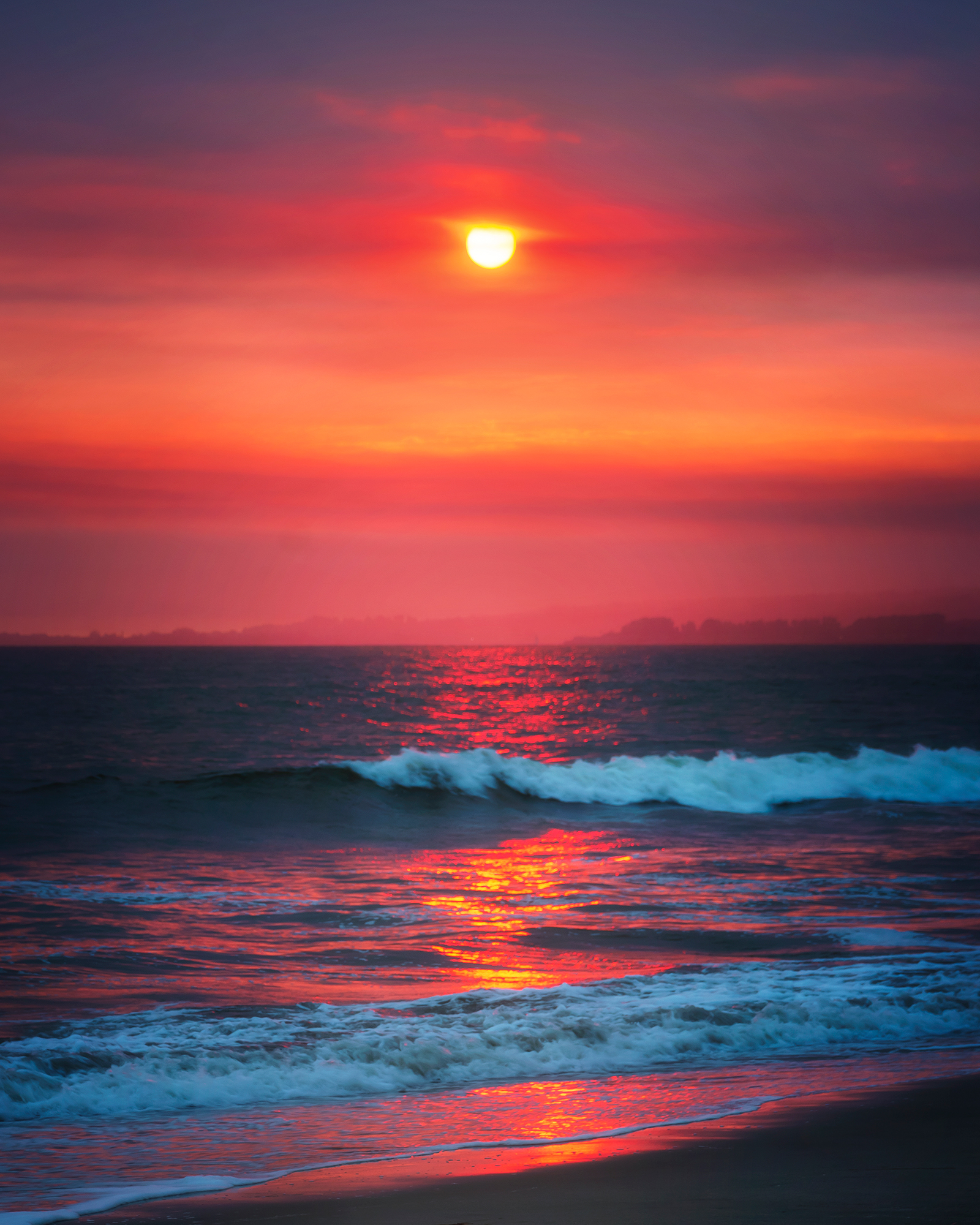 A hot pink sky over glowing blue waves.