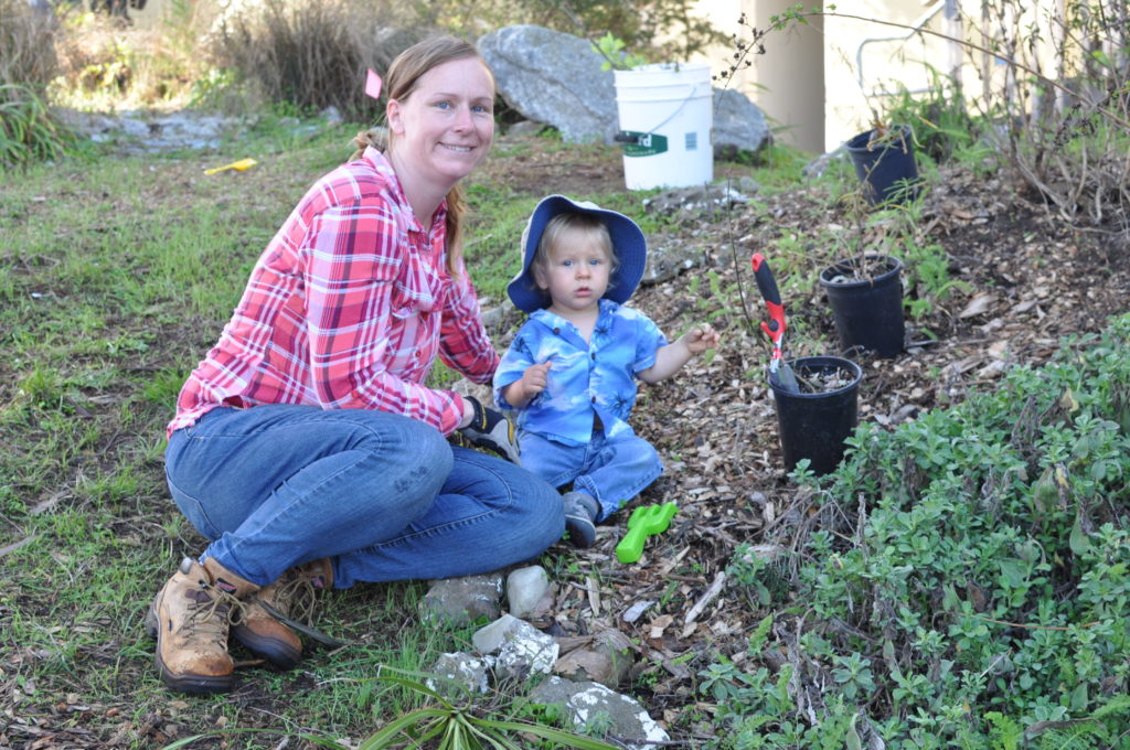 A woman and a baby working in a garden